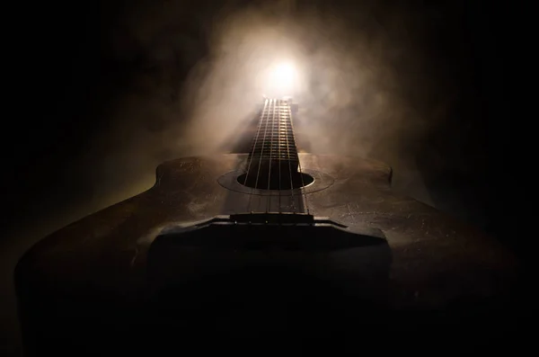 Conceito musical. Guitarra acústica isolada em fundo escuro sob feixe de luz com fumaça com espaço de cópia. Cordas de guitarra, de perto. Foco seletivo. Efeitos de fogo — Fotografia de Stock