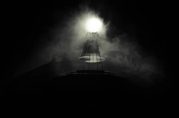 Μουσική αντίληψη. Ακουστική κιθάρα που απομονώνονται σε ένα σκοτεινό φόντο κάτω από την ακτίνα του φωτός με τον καπνό με αντίγραφο χώρο. Χορδές κιθάρας, κοντινό πλάνο. Επιλεκτική εστίαση. Εφέ φωτιά — Φωτογραφία Αρχείου