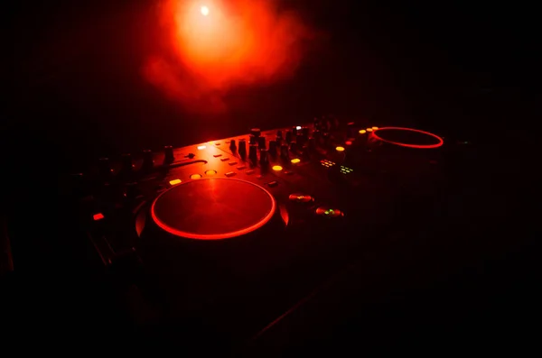 DJ Spinning, Mixing, and Scratching in a Night Club, Manos de dj ajustar varios controles de pista en la cubierta de dj, luces estroboscópicas y niebla, enfoque selectivo — Foto de Stock