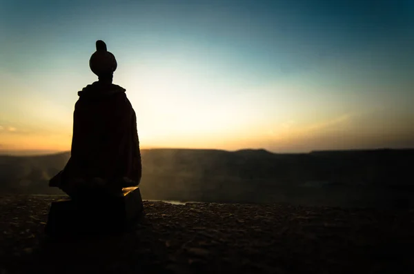 Силуэт арабского человека стоит один в пустыне и смотрит на закат с облаками тумана. Восточная сказка — стоковое фото