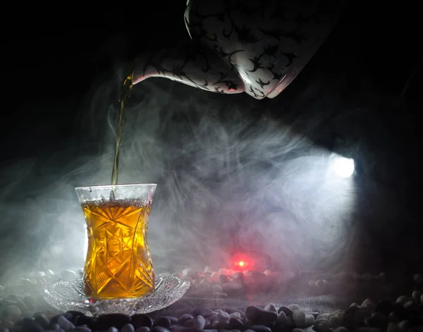 Turkish Azerbaijan tea in traditional glasse and pot on black background with lights and smoke. Armudu traditional cup — Stock Photo, Image