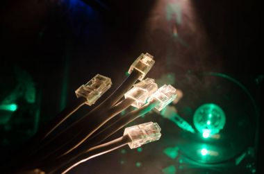 Ağ anahtarı ve ethernet kabloları, global iletişim sembolüdür. Işıklar ve duman ile koyu arka plan üzerinde renkli ağ kabloları. Seçici odak