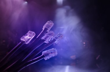 Ağ anahtarı ve ethernet kabloları, global iletişim sembolüdür. Işıklar ve duman ile koyu arka plan üzerinde renkli ağ kabloları. Seçici odak