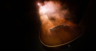Müzik konsepti. Akustik gitar ile kopya alanı dumanla ışık demeti altında karanlık bir arka plan üzerinde izole. Gitar telleri, yakın çekim. Seçici odak. Yangın etkileri