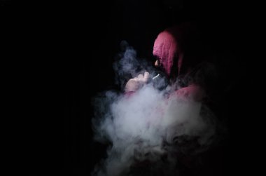Bir mod tutarak Vaping adam. Buhar bulutu. Siyah arka plan. Vaping çok duman ile elektronik sigara