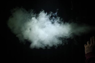 Bir mod tutarak Vaping adam. Buhar bulutu. Siyah arka plan. Vaping çok duman ile elektronik sigara
