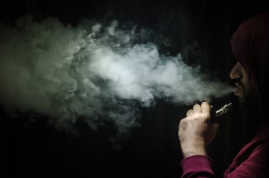 Bir mod tutarak Vaping adam. Buhar bulutu. Siyah arka plan. Vaping çok duman ile elektronik sigara
