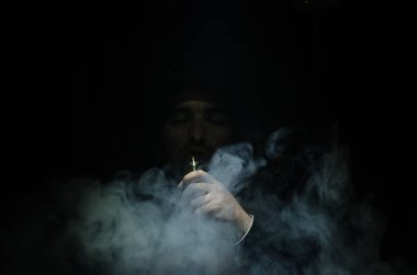 Bir mod tutarak Vaping adam. Buhar bulutu. Siyah arka plan. Vaping çok duman ile elektronik sigara
