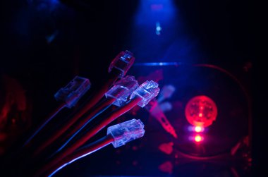 Ağ anahtarı ve ethernet kabloları, global iletişim sembolüdür. Işıklar ve duman ile koyu arka plan üzerinde renkli ağ kabloları. Seçici odak