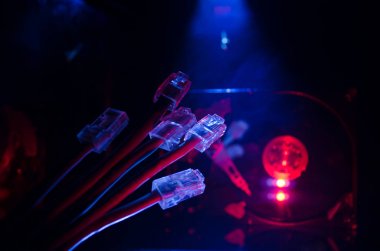 Ağ anahtarı ve ethernet kabloları, global iletişim sembolüdür. Işıklar ve duman ile koyu arka plan üzerinde renkli ağ kabloları. Seçici odak