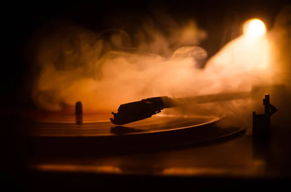 Turntable vinyl record player. Retro audio equipment for disc jockey. Sound technology for DJ to mix & play music. Vinyl record being played against burning fire background with smoke. Vintage — Stock Photo, Image