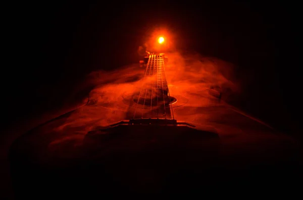 音楽のコンセプト。コピー スペースと煙と光のビームの下で暗い背景に分離されたアコースティック ・ ギターです。ギターの弦をクローズ アップ。選択と集中。火災の効果 — ストック写真
