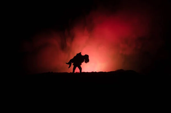 Een silhouet van een man die vasthouden aan de vrouw. Redding redder concept. Ontsnappen uit brand of gevaar. Zandloper, vuur — Stockfoto