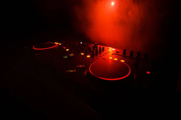 DJ spinnen, mixen en scratchen in een nachtclub, handen van dj tweak verschillende track besturingselementen op dj's dek, strobe lights en mist, selectieve aandacht — Stockfoto