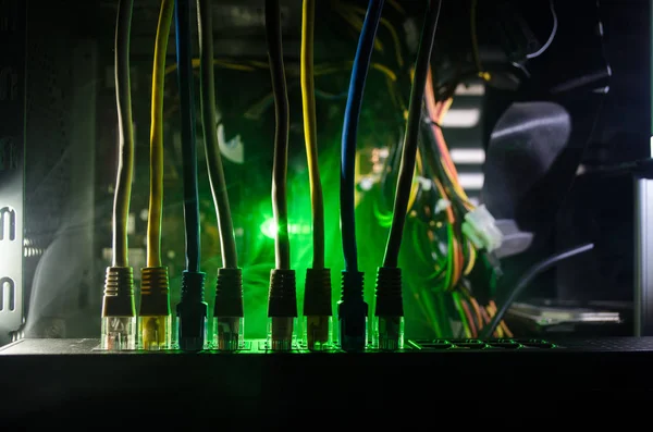 Network switch and ethernet cables, symbol of global communications. Colored network cables on dark background with lights and smoke. Selective focus — Stock Photo, Image