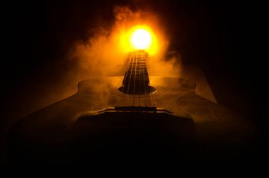 Müzik konsepti. Akustik gitar ile kopya alanı dumanla ışık demeti altında karanlık bir arka plan üzerinde izole. Gitar telleri, yakın çekim. Seçici odak. Yangın etkileri