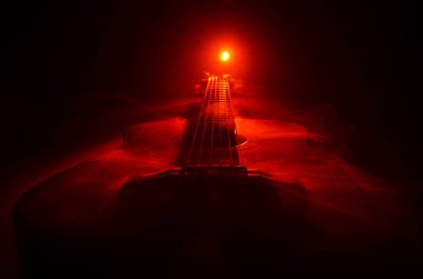 Müzik konsepti. Akustik gitar ile kopya alanı dumanla ışık demeti altında karanlık bir arka plan üzerinde izole. Gitar telleri, yakın çekim. Seçici odak. Yangın etkileri