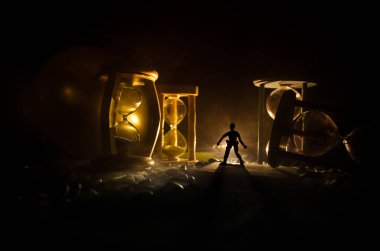 Zaman kavramı. Duman ile hourglasses ve karanlık bir arka plan ışıkları arasında duran bir adam silüeti.