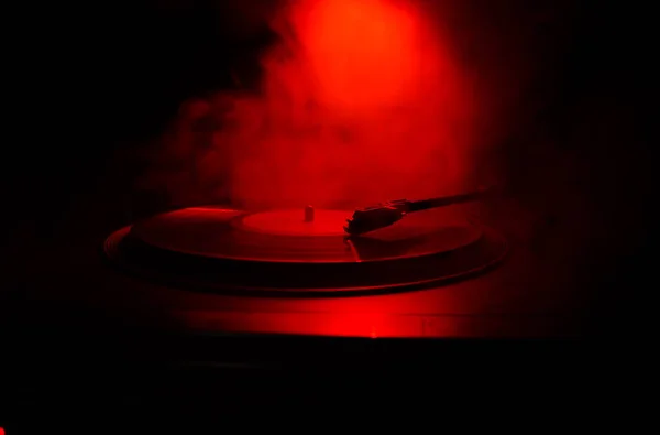 Turntable vinyl record player. Retro audio equipment for disc jockey. Sound technology for DJ to mix & play music. Vinyl record being played against burning fire background with smoke. Vintage — Stock Photo, Image