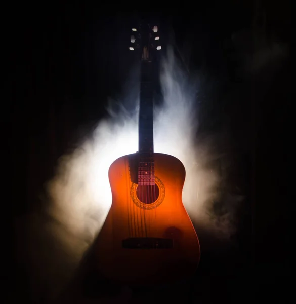 Concepto musical. Guitarra acústica aislada sobre un fondo oscuro bajo haz de luz con humo con espacio de copia. Cuerdas de Guitarra, de cerca. Enfoque selectivo. Efectos de fuego — Foto de Stock