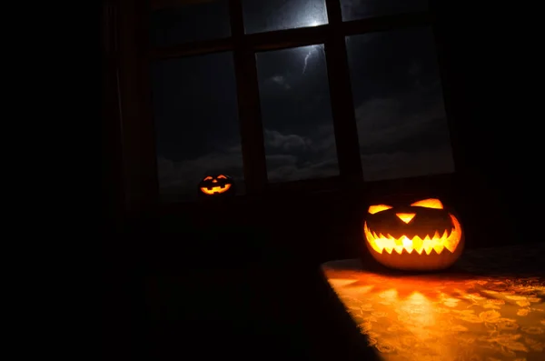 Gruseliger Halloween-Kürbis in der Nacht im mystischen Hausfenster oder Halloween-Kürbis in der Nacht auf Zimmer mit blauem Fenster. Symbol von halloween im Fenster. — Stockfoto