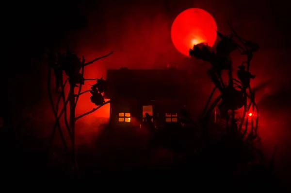 Old house with a Ghost in the moonlit night or Abandoned Haunted Horror House in fog. Old mystic villa with surreal big full moon. Horror Halloween concept.