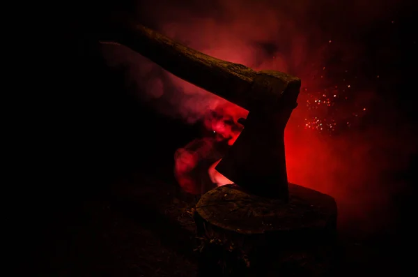 Staré ax připojené k kmen stromu na horor červené zamlžené pozadí. Strašidelné Halloween téma maniak zabiják zbraní — Stock fotografie