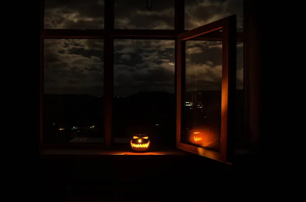 Scary Halloween pumpkin in the mystical house window at night or halloween pumpkin in night on room with blue window. Symbol of halloween in window. — Stock Photo, Image