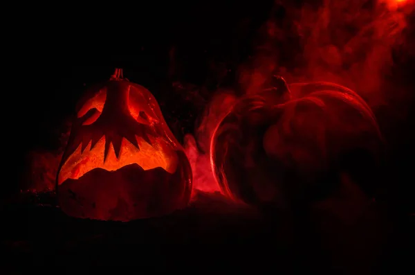 Calabazas de Halloween sonrisa y ojos rasgados para la noche de fiesta. Vista de cerca de la aterradora calabaza de Halloween con los ojos brillando en el interior en el fondo negro — Foto de Stock