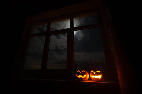 Calabaza de Halloween miedo en la ventana de la casa mística por la noche o calabaza de Halloween en la noche en la habitación con ventana azul. Símbolo de halloween en ventana . —  Fotos de Stock