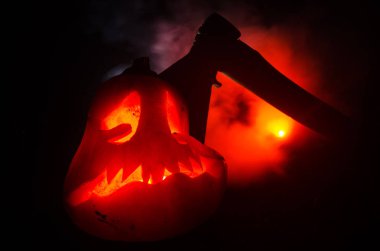 Korkunç turuncu kabak oyma gözleri ve yanan mumlar ve bir balta yangın gökyüzü karanlık bir zemin üzerine ile bir gülümseme ile. Cadılar Bayramı partisi için. Boş alan.