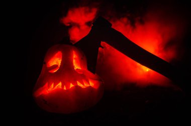 Korkunç turuncu kabak oyma gözleri ve yanan mumlar ve bir balta yangın gökyüzü karanlık bir zemin üzerine ile bir gülümseme ile. Cadılar Bayramı partisi için. Boş alan.