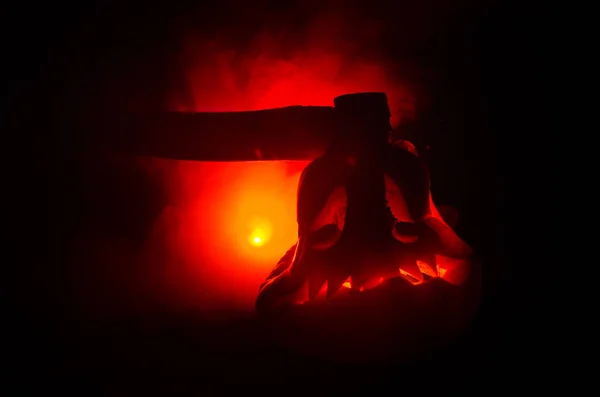 Abóbora laranja assustadora com olhos esculpidos e um sorriso com velas em chamas e um machado em um fundo escuro com céu de fogo. Para a festa de Halloween. Espaço vazio. . — Fotografia de Stock