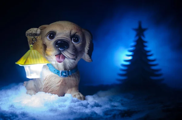 Spielzeughund - ein Symbol des neuen Jahres unter dem Schnee vor dem Hintergrund von Tannenzweigen. Der Hund des Spielzeugherstellers als Symbol für das neue Jahr 2018 mit einer weihnachtlichen Inschrift — Stockfoto