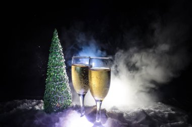 Flüt çifti ve şişe şampanya ile kar koyu arka plan üzerinde Noel ağacına yılbaşı kutlama arka plan.