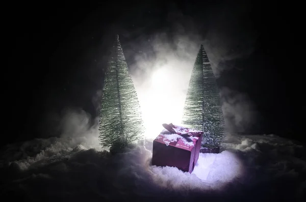 Röd gåva rutan och Gran julgran på snö. Jul hem dekoration med snö och träd på en mörk bakgrund med kopia utrymme — Stockfoto