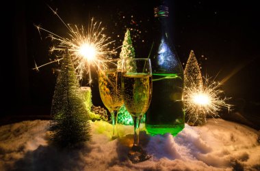 Flüt çifti ve şişe şampanya ile kar koyu arka plan üzerinde Noel ağacına yılbaşı kutlama arka plan.