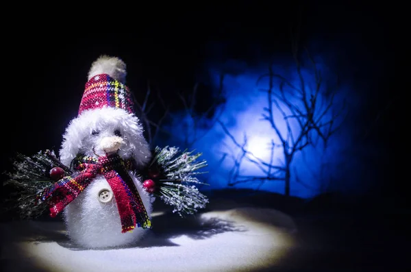Новий рік. Сніговик випускає подарунки на Новий рік. Білий сніговик, оточений ялинками на вечірньому тлі. Декорування іграшок — стокове фото