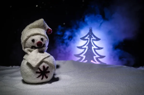 Новий рік. Сніговик випускає подарунки на Новий рік. Білий сніговик, оточений ялинками на вечірньому тлі. Декорування іграшок — стокове фото