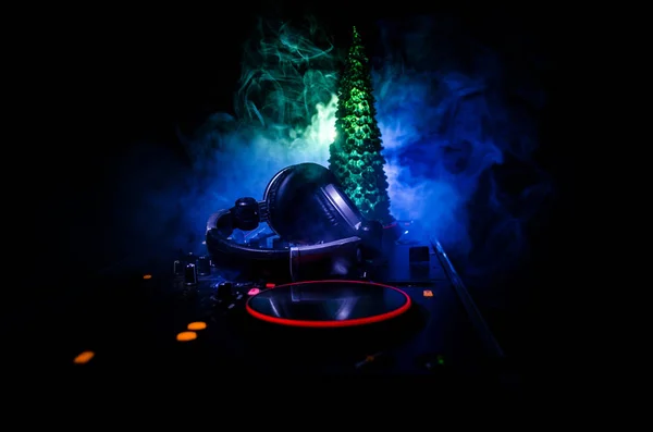 DJ mixer s sluchátka na pozadí temné noční klub s Evou nový rok vánoční stromeček. Zavřete pohled na novoroční prvků či symbolů (Santa Clause, sněhulák, pes 2018, krabičky) na stole Dj. tónovaný — Stock fotografie