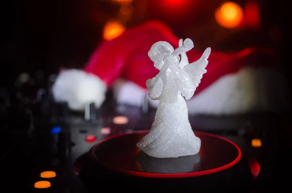Dj mixer with headphones on dark nightclub background with Christmas tree New Year Eve. Close up view of New Year elements or symbols (Santa Clause, Snowman, Dog 2018, gift box) on a Dj table. toned