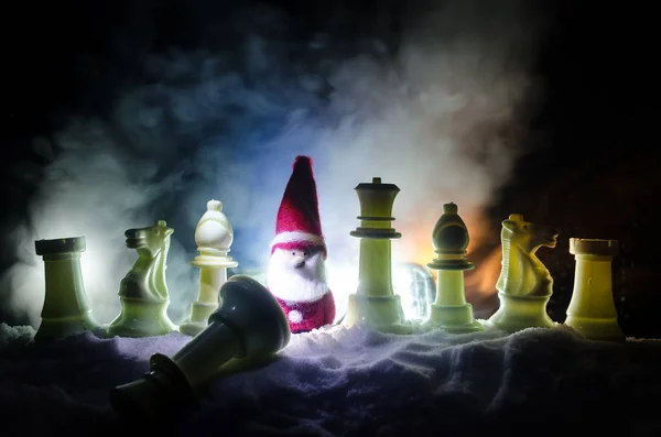 Chess in the snow. winter concept. Christmas or New Year present on a chessboard with Santa Claus on a dark background. Copy space.