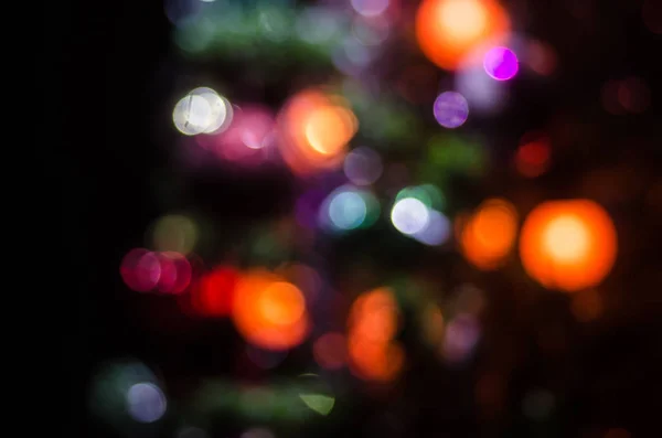 Pino de Navidad desenfocado. Luces de guirnalda de colores están brillando en el fondo. Luces eléctricas rojas, azules y amarillas — Foto de Stock