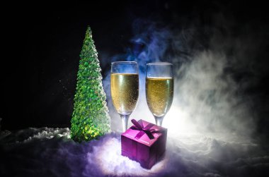 Flüt çifti ve şişe şampanya ile kar koyu arka plan üzerinde Noel ağacına yılbaşı kutlama arka plan.
