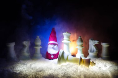 Satranç karda. Kış konsepti. Noel ve yeni yıl bir satranç tahtası üzerinde mevcut karanlık bir arka plan üzerinde Noel Baba ile. Kopya alanı.