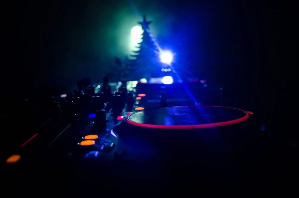DJ mixer met koptelefoon op donkere nachtclub achtergrond met kerstboom New Year Eve. Close-up van Nieuwjaar elementen of symbolen (Kerstman, sneeuwman, hond 2018, luxe-geschenketui) op een Dj tafel. toned — Stockfoto