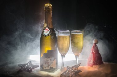 Yılbaşı kutlama ve arka plan flüt çifti şişe şampanya ile karlı koyu tonda sisli arka plan üzerinde Noel öznitelik (veya öğe). Seçici odak.