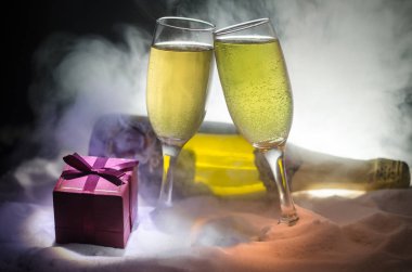 Yılbaşı kutlama ve arka plan flüt çifti şişe şampanya ile karlı koyu tonda sisli arka plan üzerinde Noel öznitelik (veya öğe). Seçici odak.