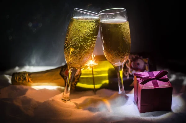 Fondo de celebración de Nochevieja con un par de flautas y una botella de champán con atributos navideños (o elementos) sobre fondo nevado de niebla oscura. Enfoque selectivo . — Foto de Stock