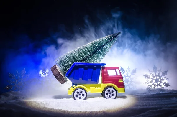 Miniature car with fir tree on Snowy Winter Fores, or toy car carrying a christmas tree and at night time — Stock Photo, Image